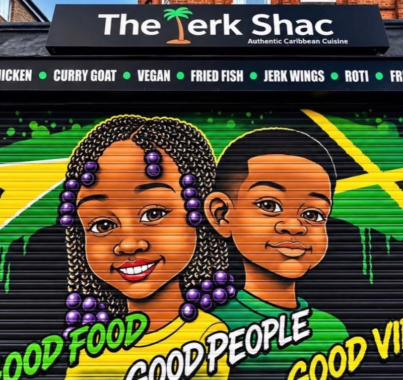 Hand-painted shop shutter by Master Skosh for The Jerk Shac, showing two smiling children in front of the Jamaican flag